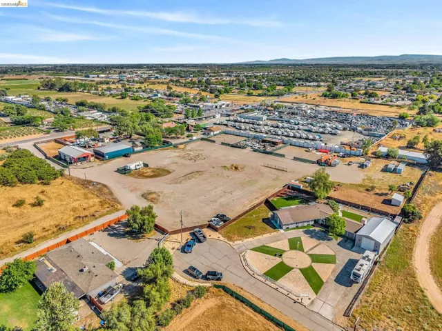 Expansive aerial showcasing a large land parcel with surrounding agricultural fields and a distant residential area