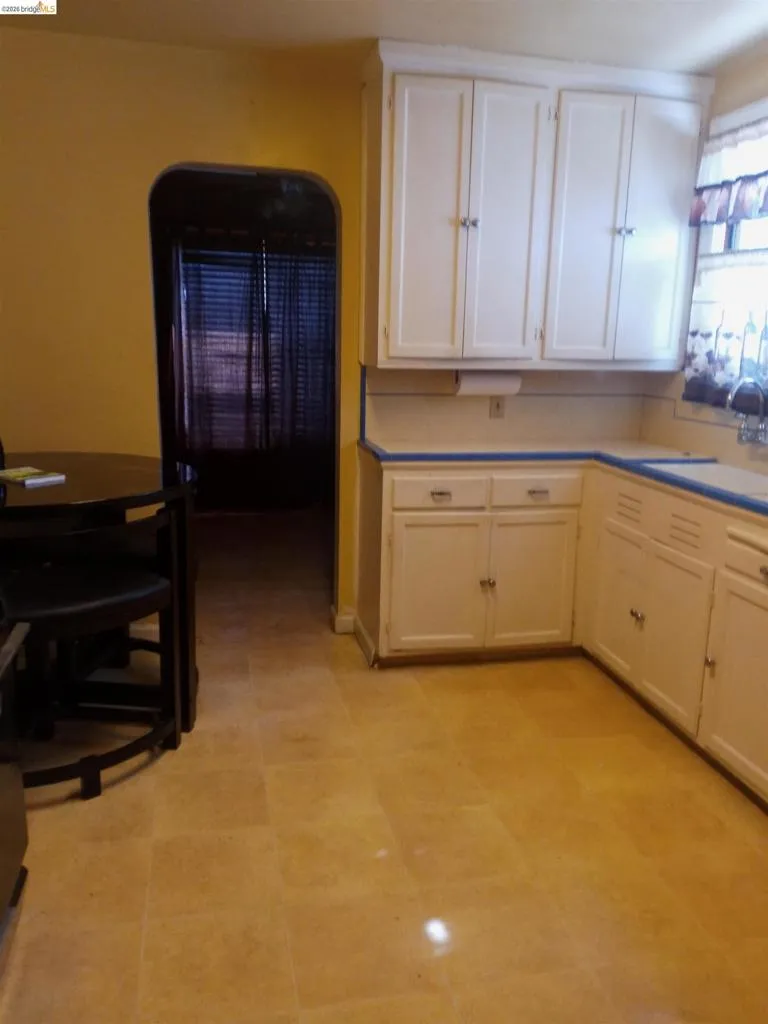 Kitchen area featuring white cabinetry with silver-tone hardware, a light-toned countertop, and tan tile flooring