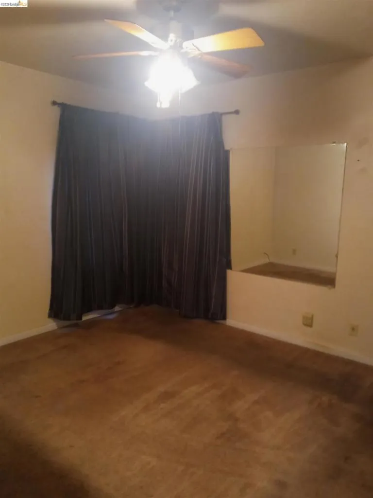 Carpeted interior space featuring a ceiling fan with integrated lighting