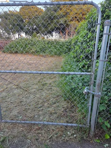 Chain-link fence gate opening to a substantial outdoor space