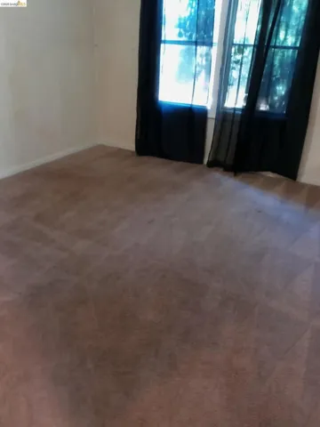 Carpeted room featuring a window with sheer dark curtains