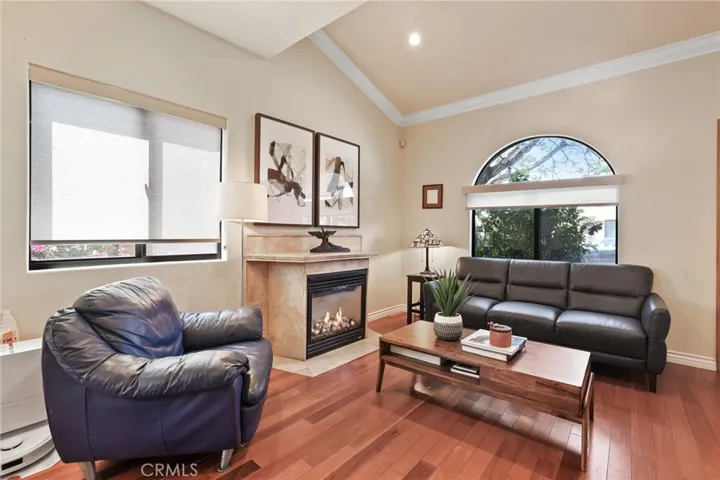 Living room view featuring beautiful arched window and vaulted ceiling.