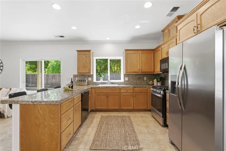 Open kitchen with bar seating, newer sink, stainless steel appliances and recessed lighting.