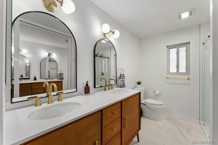 Upgraded modern primary bathroom with mid-century modern double vanity from West Elm complete with brass plumbing fixtures.