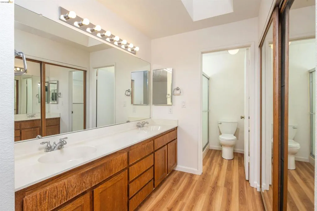 Dual vanity with wood-finish cabinetry, integrated white sinks, and chrome faucets