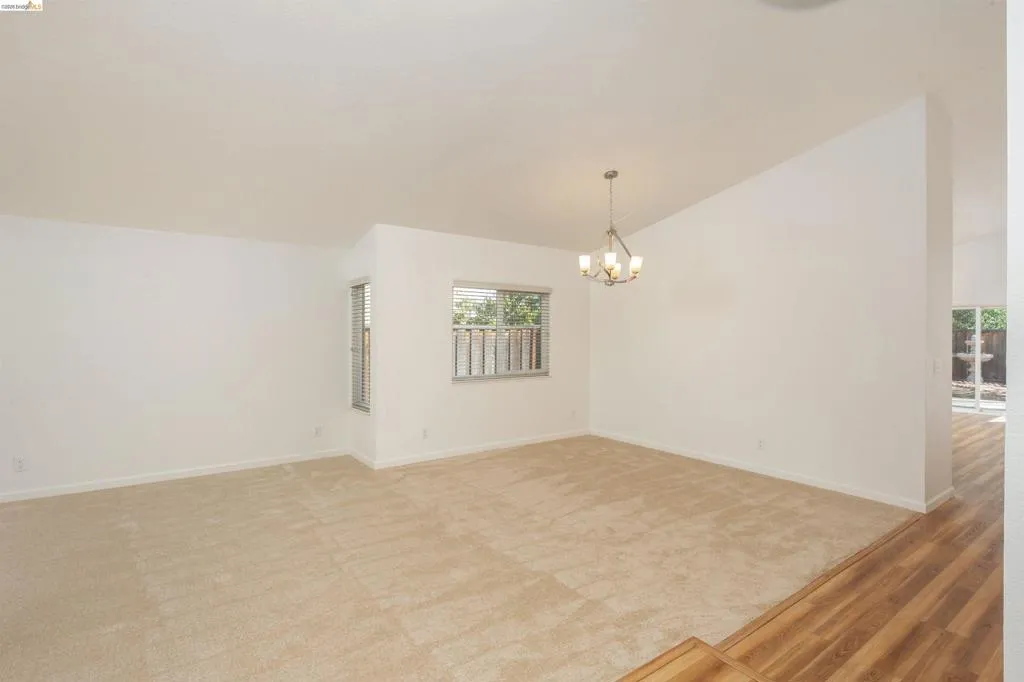 Spacious room featuring vaulted ceilings and a multi-arm chandelier