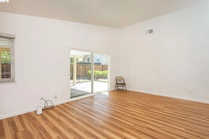 Spacious room featuring wood-finish flooring, white walls, and a high vaulted ceiling