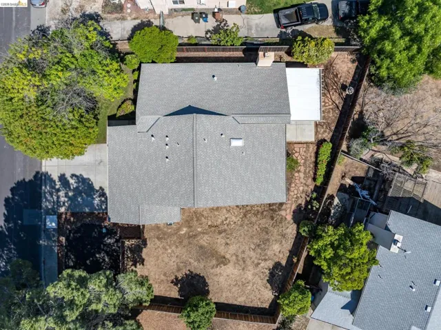 Asphalt shingle roofing with multiple roof vents, a paved driveway, and established perimeter fencing