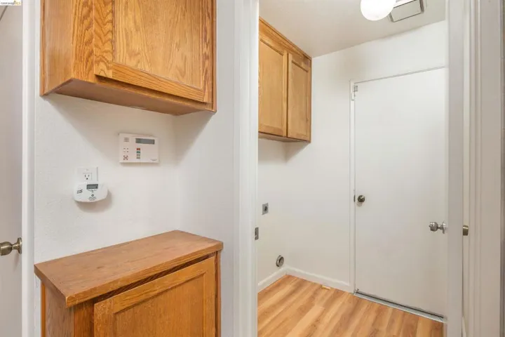 Dedicated laundry area featuring wood-finish flooring, overhead cabinetry, and appliance connections