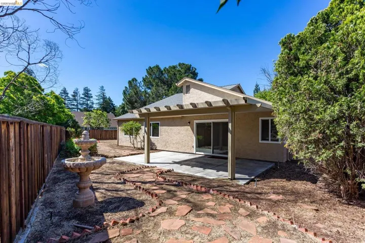 Backyard featuring a covered patio with pergola, sliding glass door, and a stone fountain