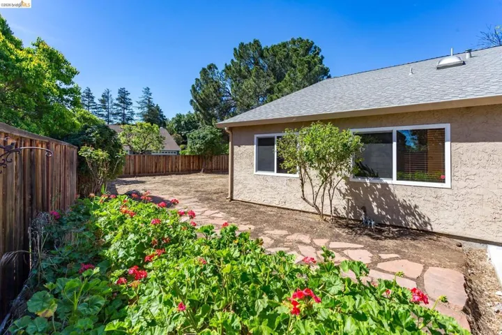 Expansive backyard featuring a natural stone pathway, mature plantings, and a wood fence