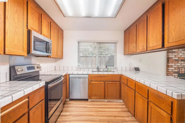 Kitchen featuring wood-finish cabinetry, tile countertops, and stainless steel appliances