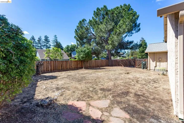 Spacious backyard featuring a wood fence perimeter and mature trees