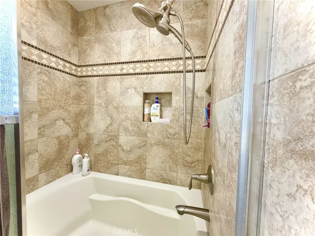 Upgraded bathroom with tiled shower/tub and modern fixtures.
