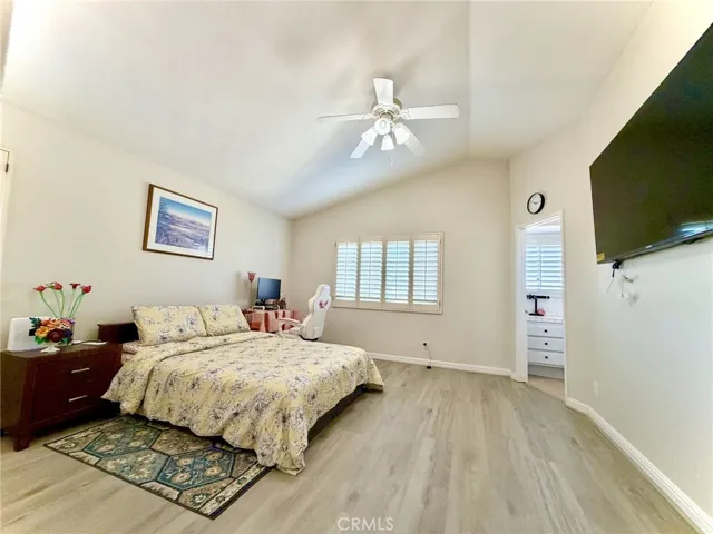 Beautiful high-ceiling primary bedroom with wood flooring and natural light.