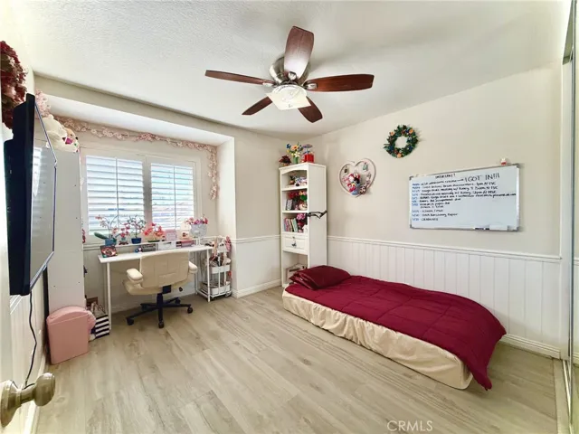 Bright bedroom with window seating area and wood flooring.