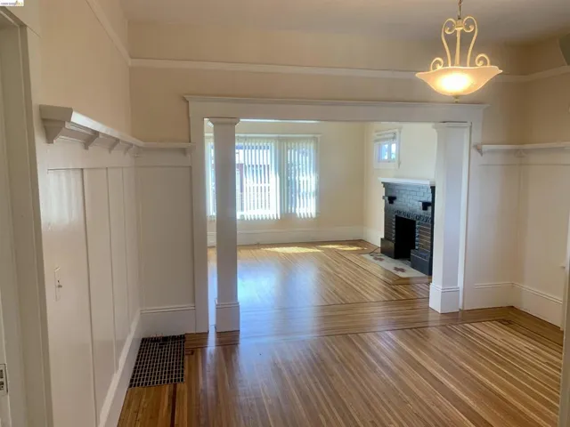 Unfurnished living room featuring light wood-style flooring, a brick fireplace, and a decorative wall