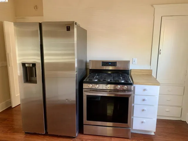 Kitchen featuring stainless steel appliances, dark wood finished floors, and white cabinetry