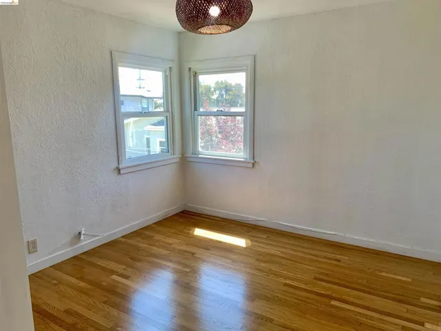 Empty room with a textured wall and light wood-type flooring