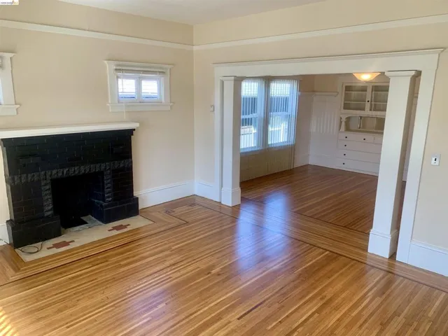 Unfurnished living room with wood finished floors and a brick fireplace