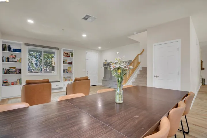 Open-concept living area featuring light wood-finish flooring, recessed lighting, and a white interior paint palette