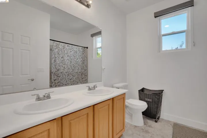 Bathroom featuring a double vanity with light wood cabinetry, white countertops, and dual undermount sinks