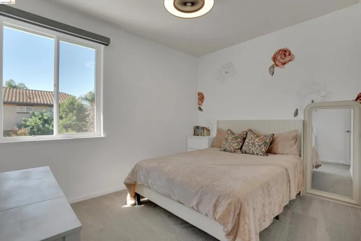 Light-filled room featuring a large window, neutral wall paint, and gray carpet flooring