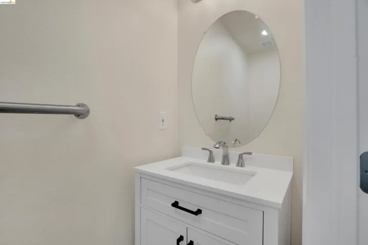White vanity with shaker-style cabinetry, black hardware, and an integrated sink with a polished chrome faucet