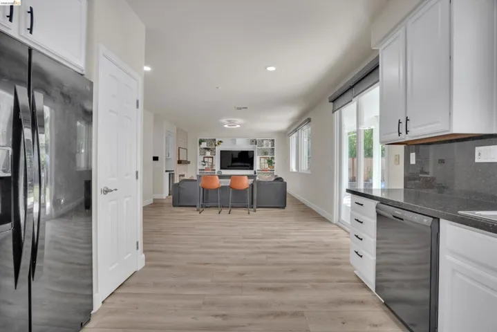 Open-concept living space featuring wood-finish flooring, recessed lighting, and white cabinetry