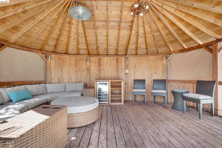 Circular wooden gazebo featuring a slatted wood ceiling, wood plank flooring, and wood panel walls