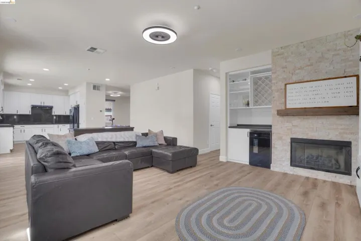 Living area featuring light wood-finish flooring and a stone-clad fireplace with a wood mantle