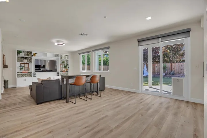 Spacious interior featuring light wood-finish flooring, recessed lighting, and a built-in media center with shelving