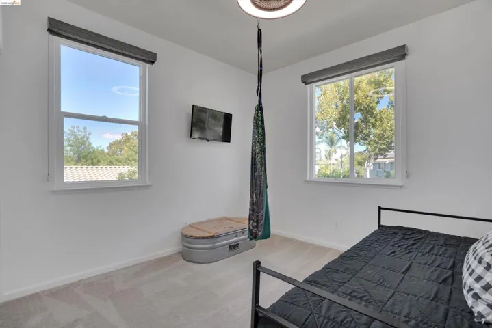 Bright room with neutral carpeting, white walls, and a contemporary ceiling light fixture