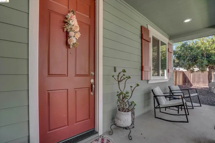 Inviting front porch featuring a paneled entry door, siding exterior, white trim, and a concrete patio