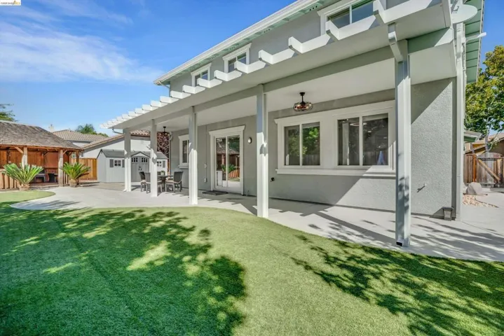 Expansive backyard featuring a covered patio with a pergola extension, artificial turf, and a built-in gazebo structure