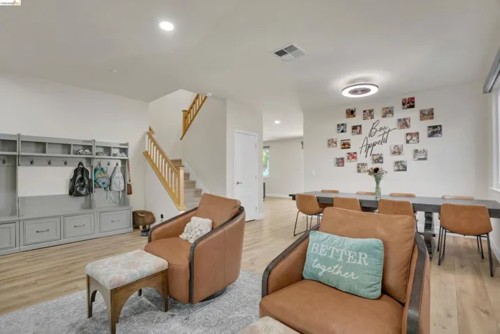 Open-concept living area featuring wood-finish flooring, recessed lighting, a built-in grey storage system with cubbies and drawers, and a staircase with natural wood railings