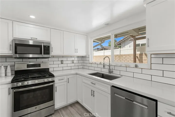 gas stove, tile backsplash, and quartz counter tops