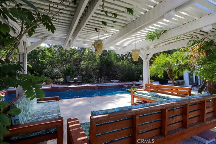 Beautifully landscaped yard with a covered pergola and multiple outdoor living areas.