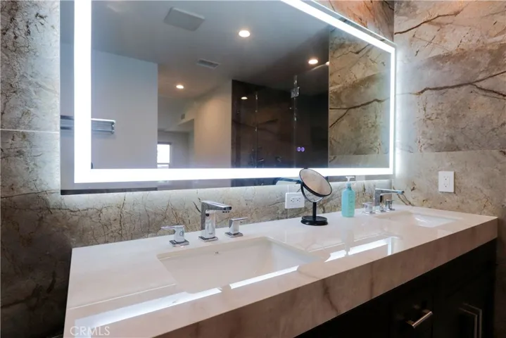 Spa-inspired primary bathroom with dual vanities and LED-lit mirror