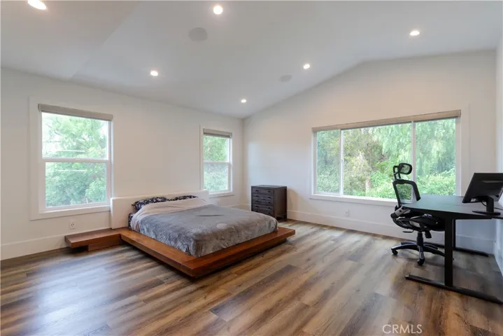 Spacious bedroom with warm wood flooring and abundant natural light
