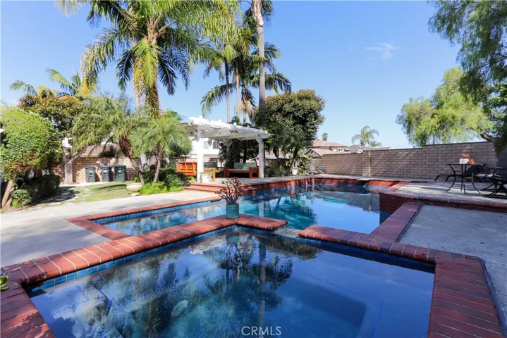 Resort-style backyard featuring a sparkling pool, spa, and lush tropical landscaping