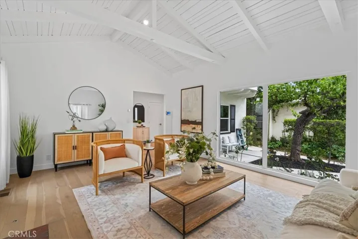 Spacious living room with large windows, vaulted ceiling, and fireplace