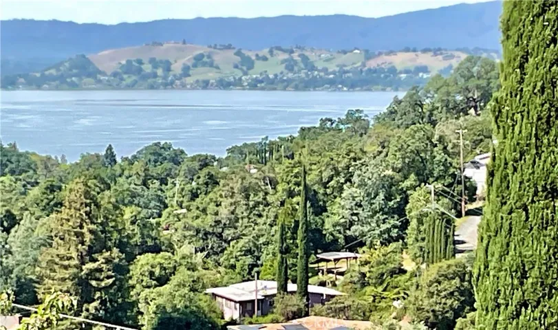 Aerial perspective of the full 4-lot estate (7252–7282 Marin St) featuring the existing home, carport, and immense privacy. This rare vantage point highlights the proximity to Clearlake and the potential for expansive panoramic views with selective clearing.