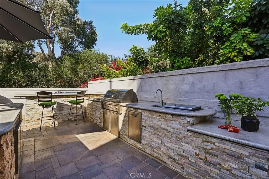 Outdoor kitchen features include BBQ, separate grill with 2 burners, sink, ice chest, trash drawer and storage