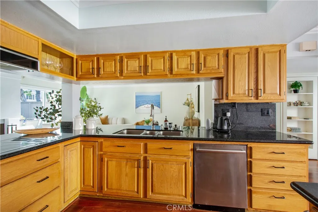 Another view of kitchen including stainless steel sink and dishwasher leading into family room.