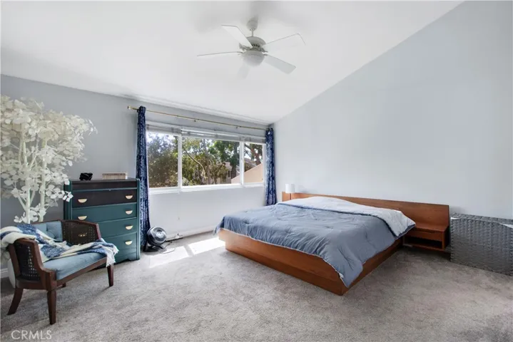 Primary bedroom including vaulted ceiling and large dual pane window leading to back patio