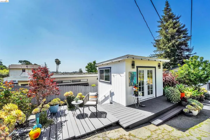 Detached auxiliary building featuring white siding, black trim windows, and French doors