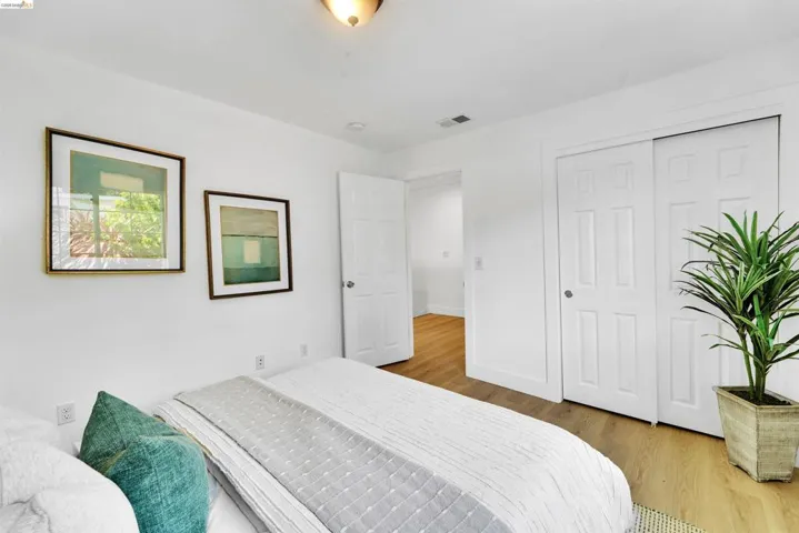 Bright interior room featuring wood-finish flooring, white walls, and a white six-panel door