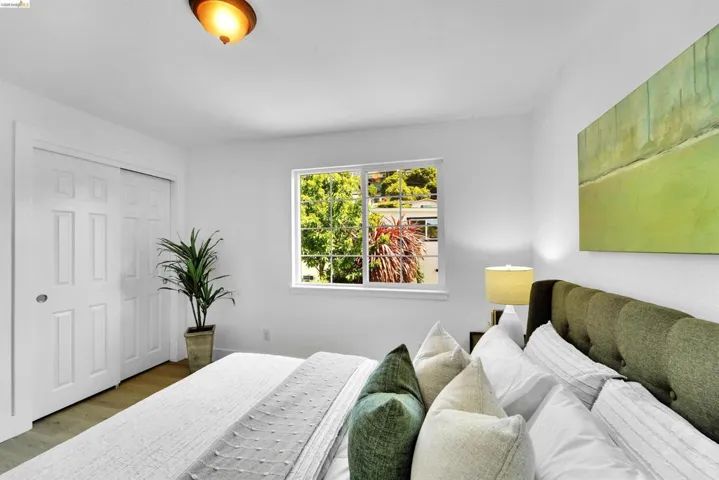 Bedroom featuring white walls, wood-finish flooring, and a window with exterior views