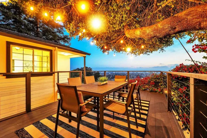 Spacious outdoor deck featuring wood-finish flooring, cable railing, and a covered patio area